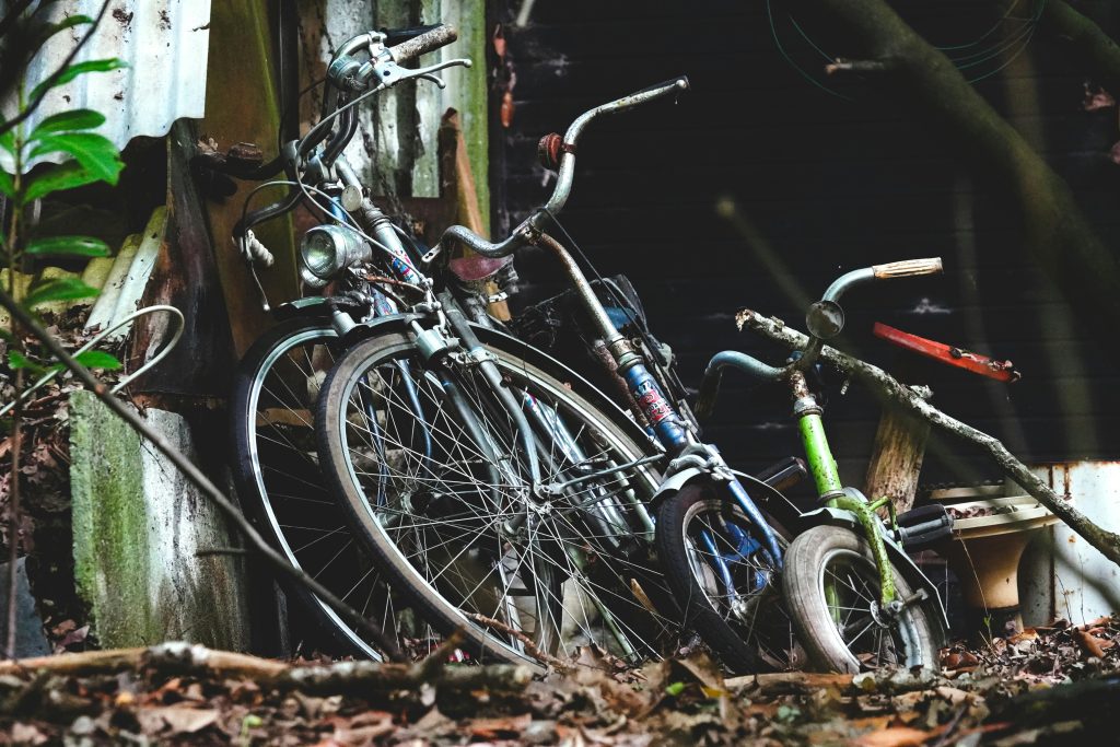 pexels-photo-33415500-33415500 Old vintage bicycles leaning against a rustic shed, overgrown with plants, evoke a nostalgic atmosphere.