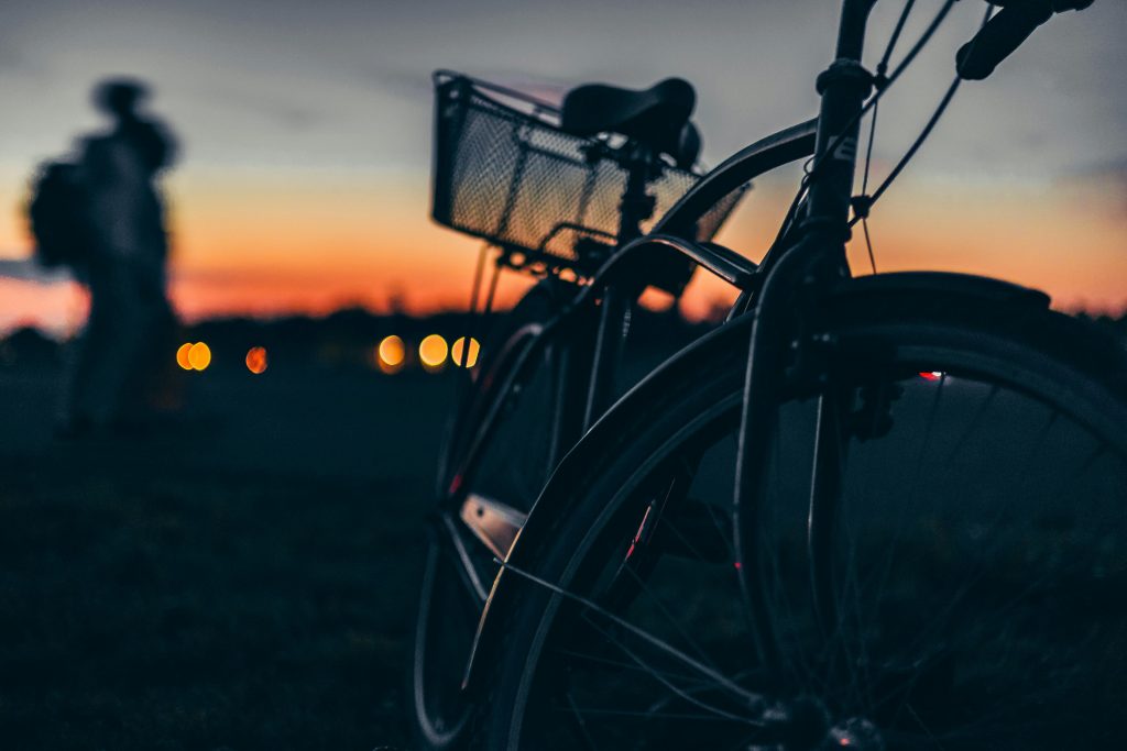 pexels-photo-33672262-33672262 Silhouette of a bicycle at sunset with a blurry person in the background.
