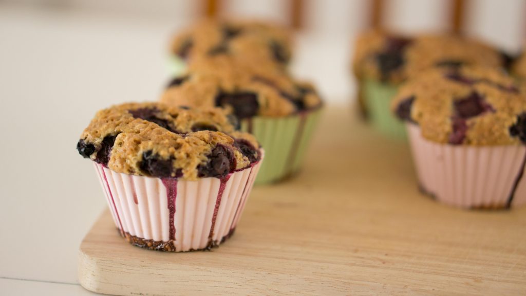 Freshly baked blueberry muffins on a wooden board, showcasing their delicious homemade look.