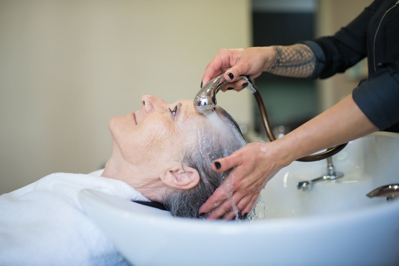 about-02 Elderly woman receiving a relaxing hair wash in a salon setting.